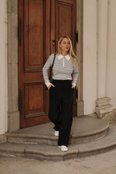 a lady n a zip-up striped knit top and a pair of black pants